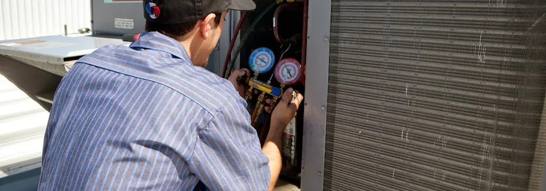 HVAC technician servicing a condenser unit in Blooming Grove